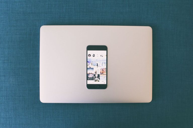 Smartphone showing social media photos on top of a laptop